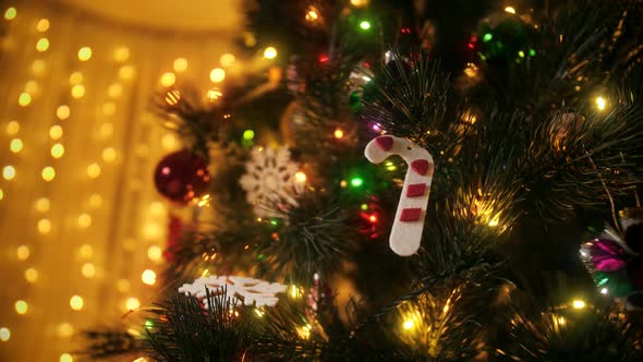 Closeup of Traditional Decorations Baubles and Light Garlands Hanging on Christmas Tree at Night