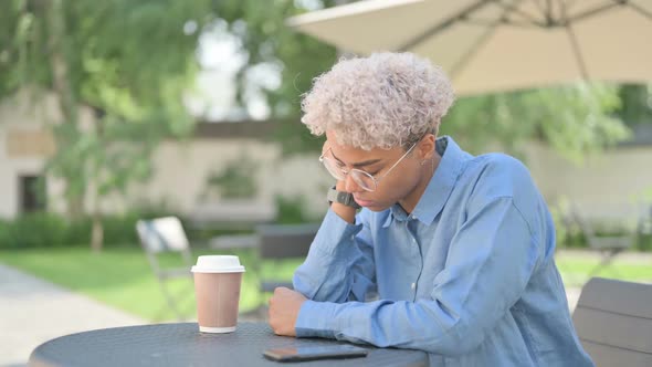 Young African Woman with Coffee Taking Nap in Outdoor Cafe