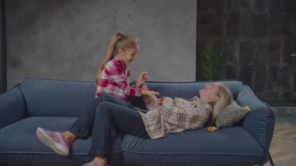 Carefree Preadolescent Girl and Mom Having Fun on Couch