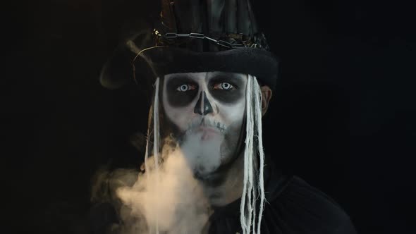 Frightening Man in Creepy Skeleton Halloween Cosplay Exhaling Cigarette Smoke From His Mouth