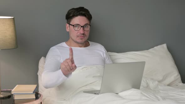 No Gesture with Finger By Middle Aged Man with Laptop in Bed 