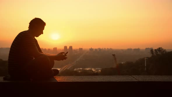 Man Texting in Sunset