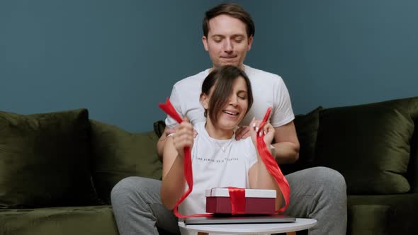 Young Lovely Couple Woman That Is Opening a Gift From Her Husband