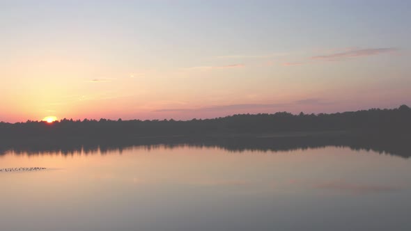 Countryside Dramatic and Colorful Sunset Flight Over a Forest Lake Aerial Shot on a Drone