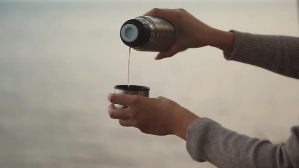 Woman Pouring Coffee Into Cup. Hot Tea From Thermos. Holiday Vacation Trip And Relaxing Moment.