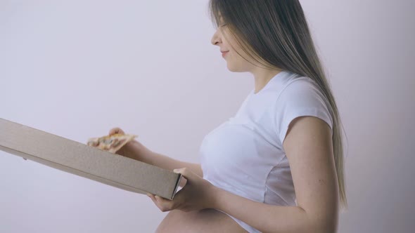 Pregnant Woman with Tummy Holds Box of Pizza at Light Wall