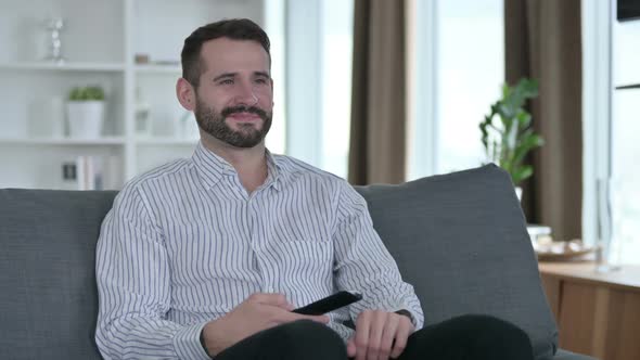 Relaxed Young Businessman Watching Television at Home 