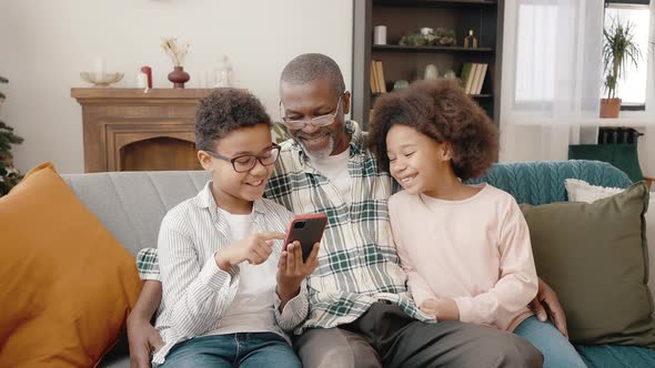 Zoom in Portrait of Happy African American Grandfather and Grandchildren Watching Digital Media on