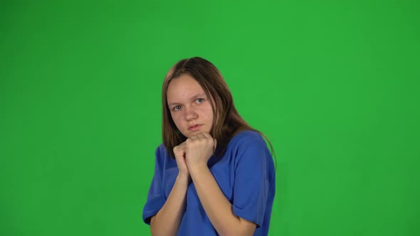 Teen Girl Is Scared and Hiding Her Face in Studio on Green Background.