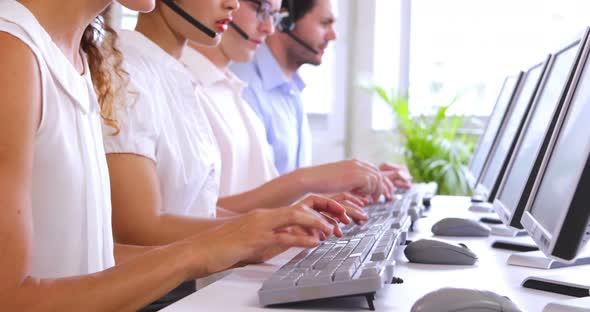 Row of Call Center Agents Typing at their Desk