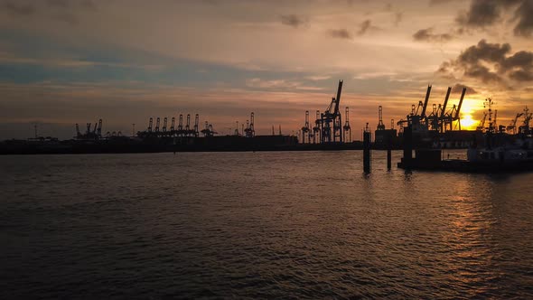 Sunset timelapse in Hamburg (Germany). Harbour sunset with boats and cranes.