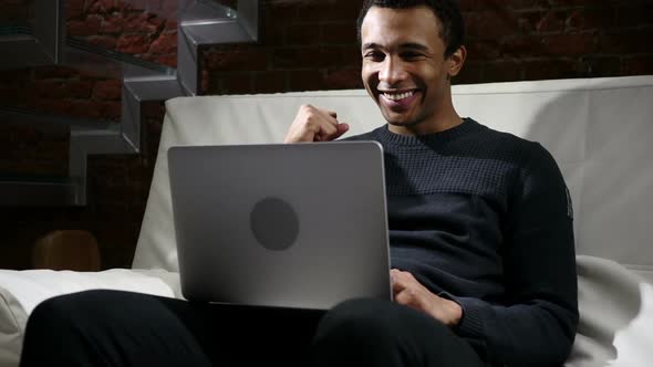 African Man Celebrating Success of Project Working on Laptop