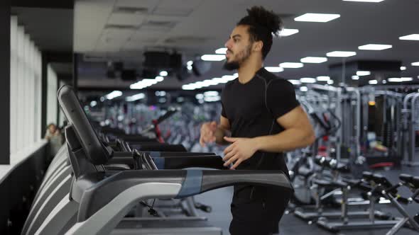 Fitness Man Training Cardio Exercise on Running Machine in Gym Side View