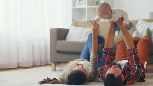 Happy Mother and Father Playing with Baby at Home