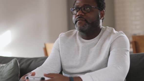 Concentrated African man playing game with gamepad