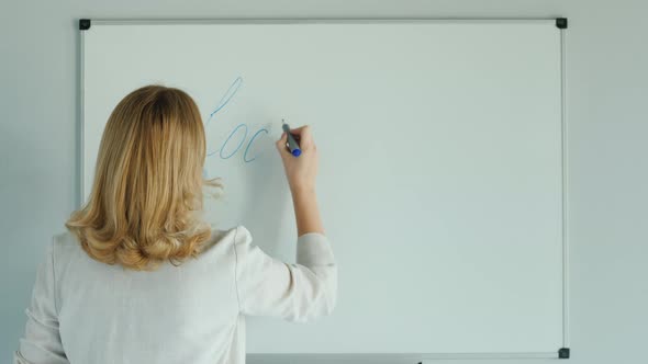 A Woman Writes a Word Lockdown on the Class Board