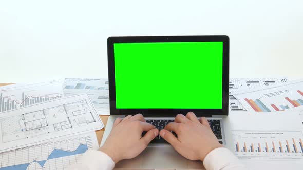 Man Hand on Laptop Keyboard with Green Screen Monitor in the Office
