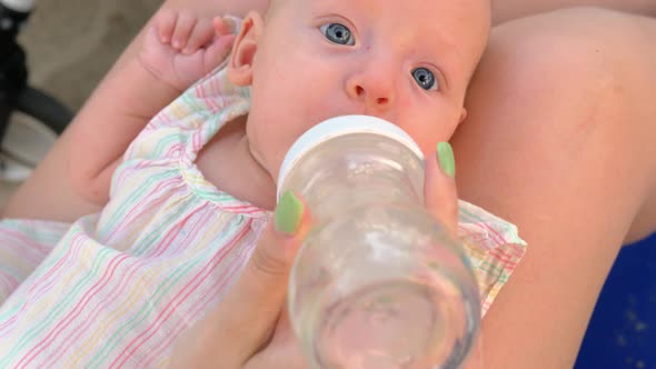 Mother Giving Baby Daughter To Drink Water From the Bottle