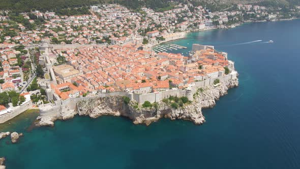 Aerial rotating shot of old town Dubrovnik, Croatia with rocky cliffs along the seaside and fortress