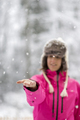 Young woman standing in a snow extending her arm in front of her to catch snow flakes - PhotoDune Item for Sale