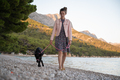 Young woman and her dog walking on pebble beach - PhotoDune Item for Sale