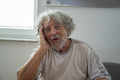 Senior man with gray curly hair leaning his head on his arm - PhotoDune Item for Sale