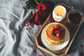 Pancakes with berries, roses flowers, cup of tea and candle in candlestick. Valentine's day concept - PhotoDune Item for Sale