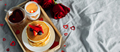 Pancakes in the shape of a heart with berries, roses flowers, cup of tea and candle in candlestick. - PhotoDune Item for Sale