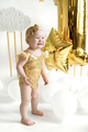 Baby in gold bodysuit on first birthday on background decorated with balloons - PhotoDune Item for Sale