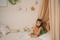 A girl in green dress sits thoughtfully in bed hugging pillow - PhotoDune Item for Sale