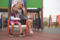 Girl with broken arm and cast with friend having fun on the playground slide. - PhotoDune Item for Sale