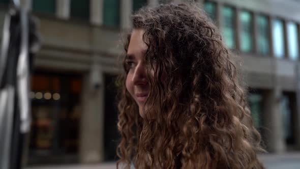 Portrait of a Young Woman with Curly Hair on a City Street. the Camera Moves Around