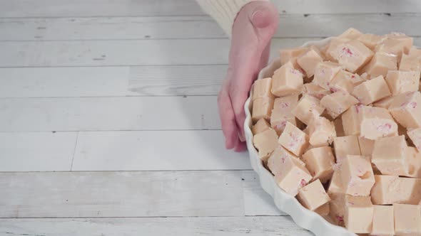 Step by step. Candy cane fudge cut in small cubes on a white serving dish.