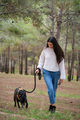Young caucasian woman walking a mixed breed dog at a pine forest. - PhotoDune Item for Sale
