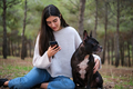 Young caucasian woman using the phone sitting at a forest with her dog . - PhotoDune Item for Sale
