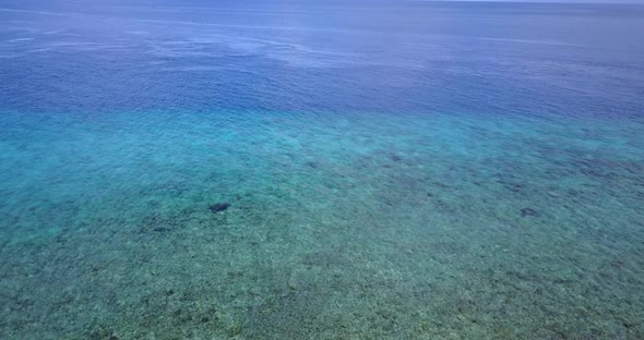 Wide overhead tourism shot of a paradise sunny white sand beach and blue ocean background in colourful