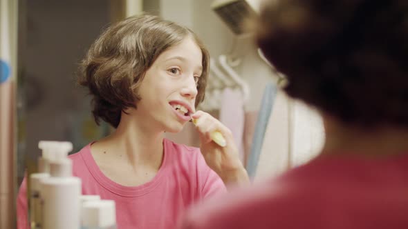 young girl brushing her teeth in front of the mirror