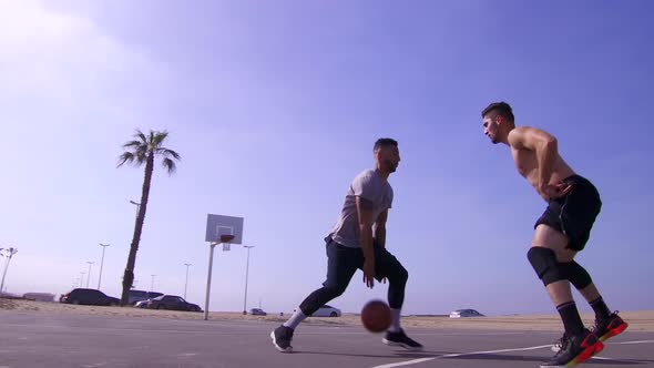 A man takes a layup shot while playing one-on-one basketball hoops on a beach court