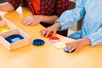 Cropped view of kids folding colorful game on table in montessori school