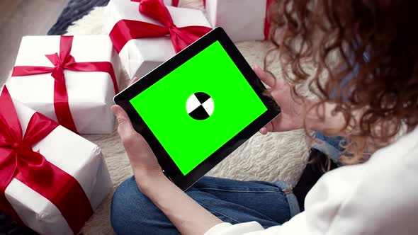 Christmas online shopping top view. Female buyer touch greenscreen of tablet, copy space.