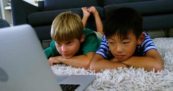 Siblings using laptop in living room