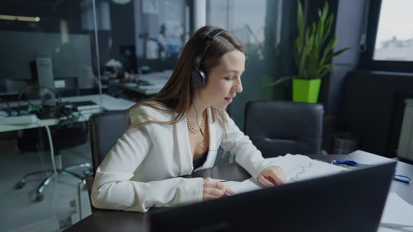 Positive Young Slim Beautiful Brunette Caucasian Woman in Headphones Working in Office