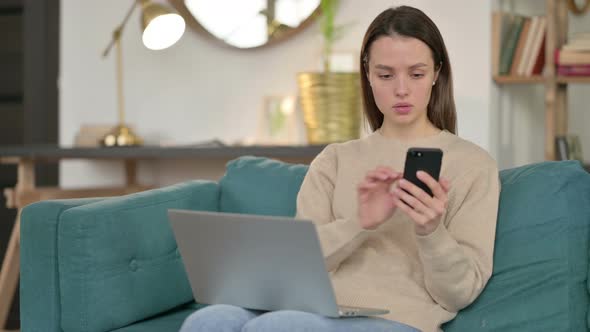 Young Woman Working on Smartphone and Laptop on Sofa 