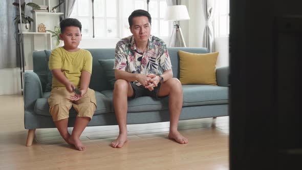 Asian Father And His Son Are Watching Tv While Spending Time Together