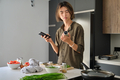 Asian young man checking recipe ingredients on mobile phone. - PhotoDune Item for Sale