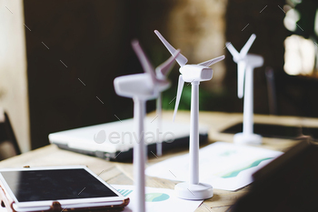 Close up of wind turbines on a table desk with data sheets, tablet and laptops