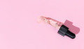 Flat lay of a pipette with pouring liquid serum on pink background - PhotoDune Item for Sale