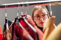 selective focus of attractive stylist in glasses looking at fashionable clothing on hangers - PhotoDune Item for Sale