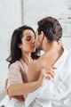 Selective focus of couple hugging and woman undressing businessman in bedroom - PhotoDune Item for Sale