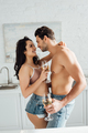 Couple with glasses of wine hugging, smiling and looking at each other in kitchen - PhotoDune Item for Sale